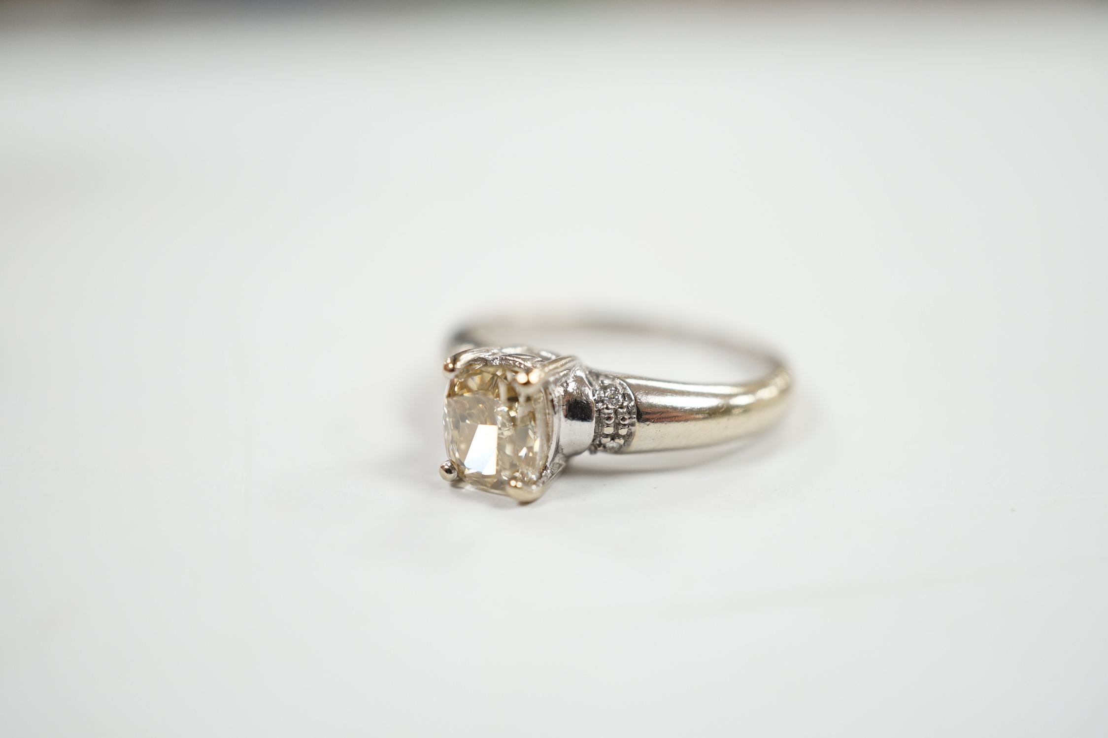 A 750 white metal and single stone oval cushion cut diamond ring, with four stone diamond chip set shoulders, size K, gross weight 3.3 grams.